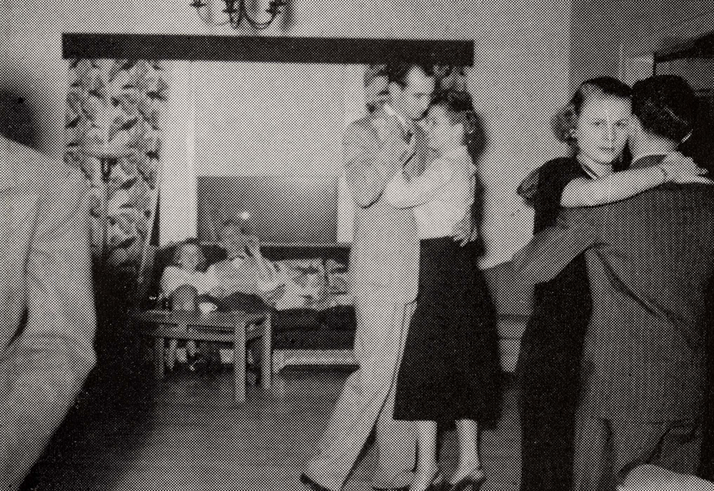 Two couples dancing while another couple sits on a couch.