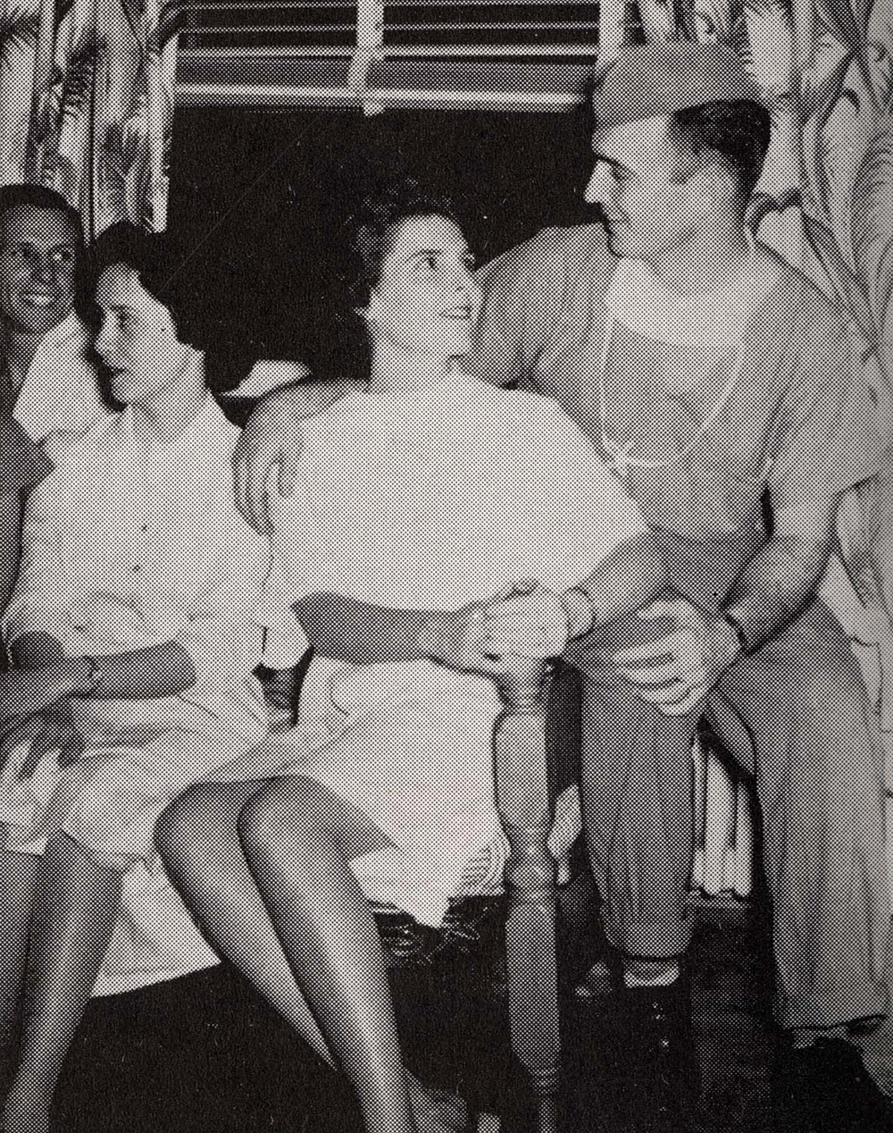 A few medical students lounge, one wearing surgical scrubs, another in a simple white dress.