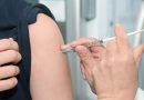 A flu vaccine needle being put into an arm.
