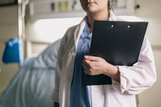 female-medical-professional-holds-clipboard-in-hospital-room