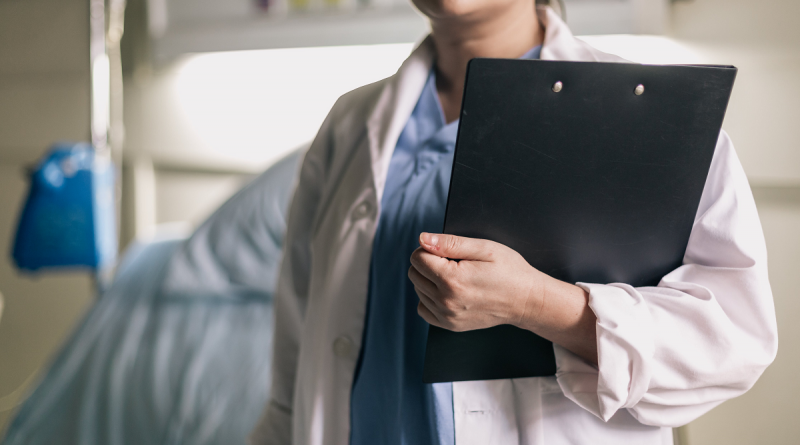 female-medical-professional-holds-clipboard-in-hospital-room