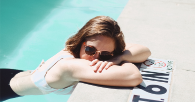 A woman wearing sunglasses in a pool, alone.