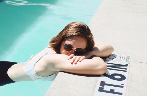 A woman wearing sunglasses in a pool, alone.