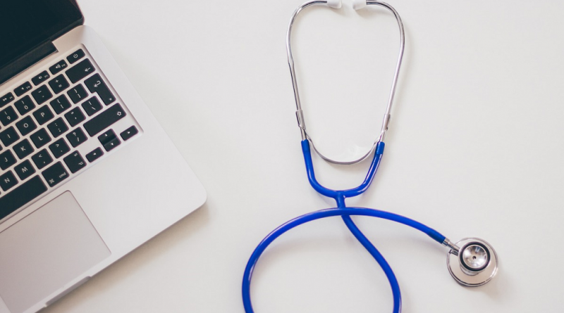 A stethoscope sitting next to a laptop