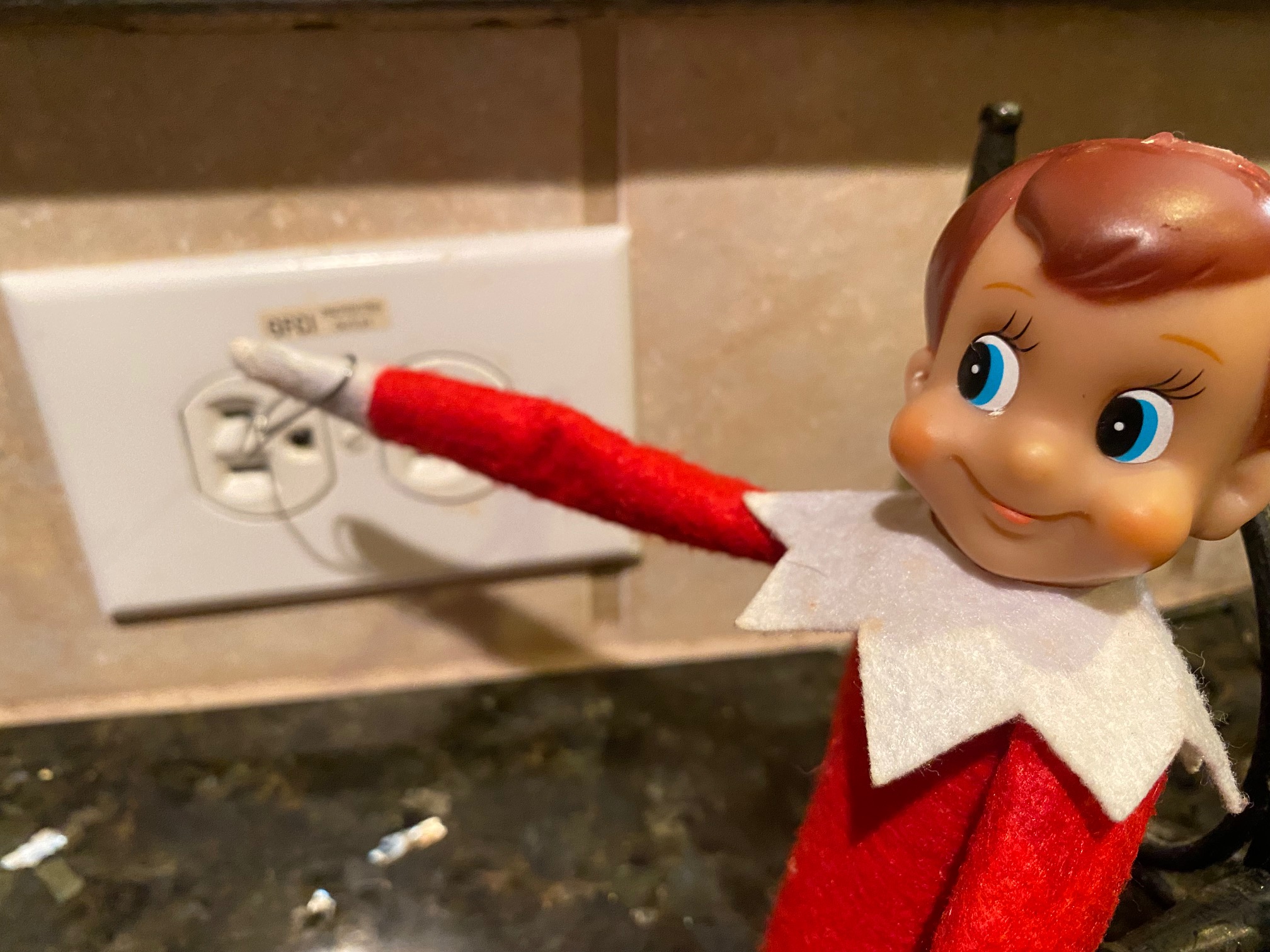 A picture of a toy elf putting a paperclip into an electric socket.