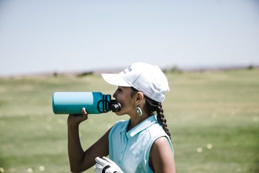 a golfer takes a drink from a water bottle
