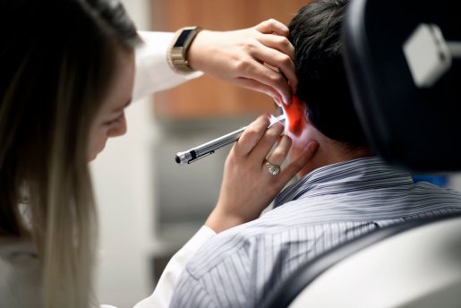 An audiologist looks into a patients ears with an otoscope.