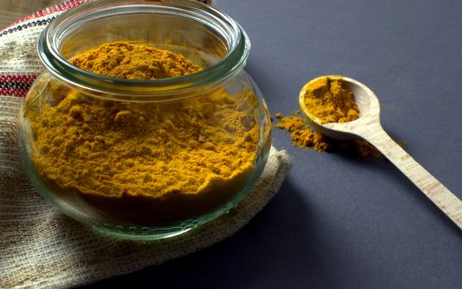 A container and spoon of tumeric.