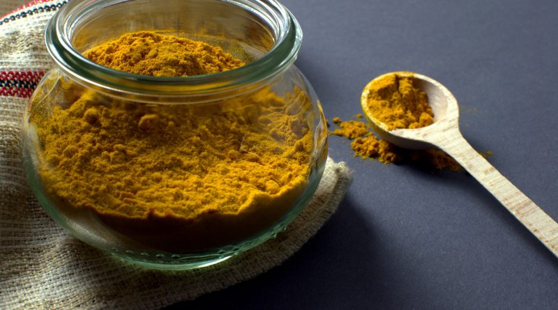 A container and spoon of tumeric.