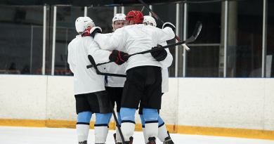 A group of hockey players hug on the ice.