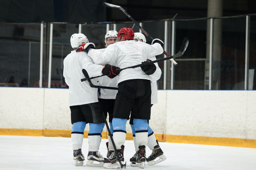 A group of hockey players hug on the ice.