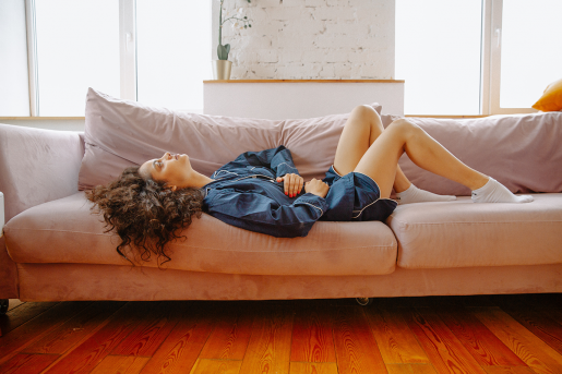 A woman reclined on a couch, seemingly in pain or discomfort