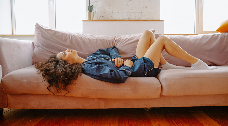 A woman reclined on a couch, seemingly in pain or discomfort