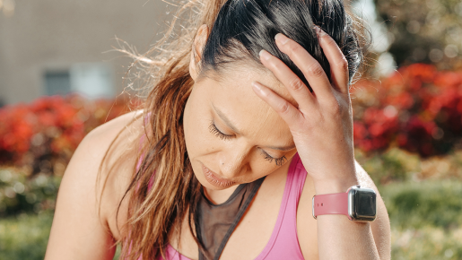 A person pausing their exercise to hold an injured head.