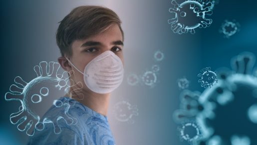 A young person wearing a face mask standing among graphic representations of the coronavirus.