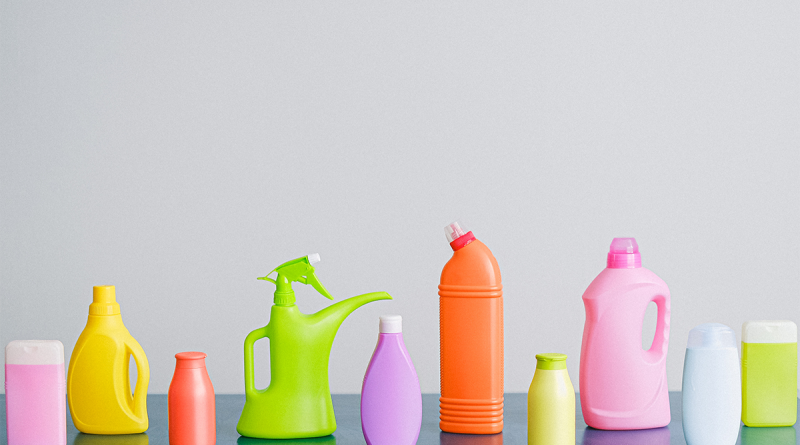 A collection of cleaning product bottles, each a different color, sitting on a table.