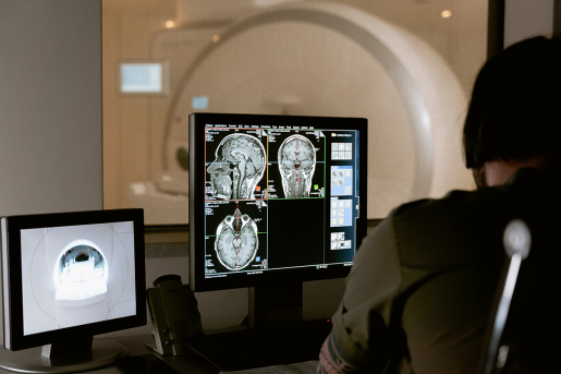 A doctor looking at brain scans from a patient, who is in an MRI machine