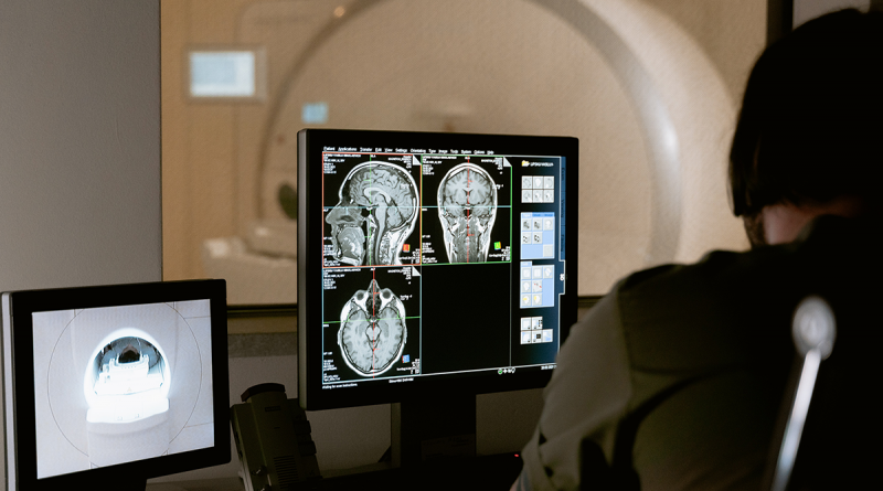 A doctor looking at brain scans from a patient, who is in an MRI machine
