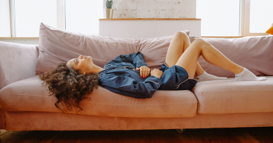 A person laying on a sofa with an uncomfortable or pained expression.