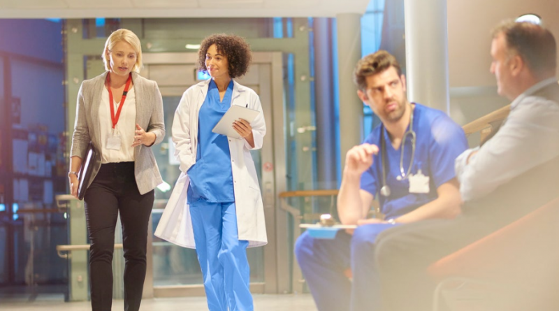 Healthcare workers walking down a hallway while having a conversation.