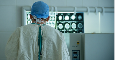 A neurosurgeon facing away from the camera while studying images of a patient.