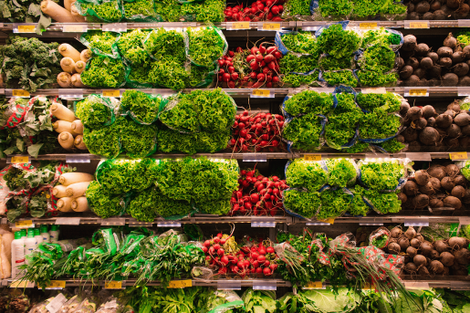A well-lit grocery store vegetable section. Six shelves full of fresh green romaine lettuce, bright red radishes and assorted root vegetables fill the screen. Everything looks fresh, healthy and delicious. 