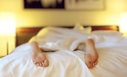 The soles of someone's feet. The person is facedown under a blanket.