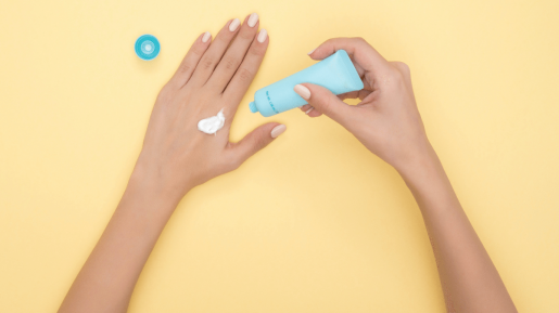 A pair of hands seen from above in the process of putting on a hand cream.