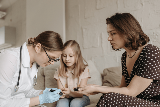 A doctor administering a diabetic blood test to a child while their parent looks on.