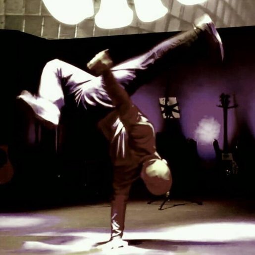 Hip replacement patient Hector Luna break dancing - upside down with one hand on the ground holding him up while his feet kick in the air.