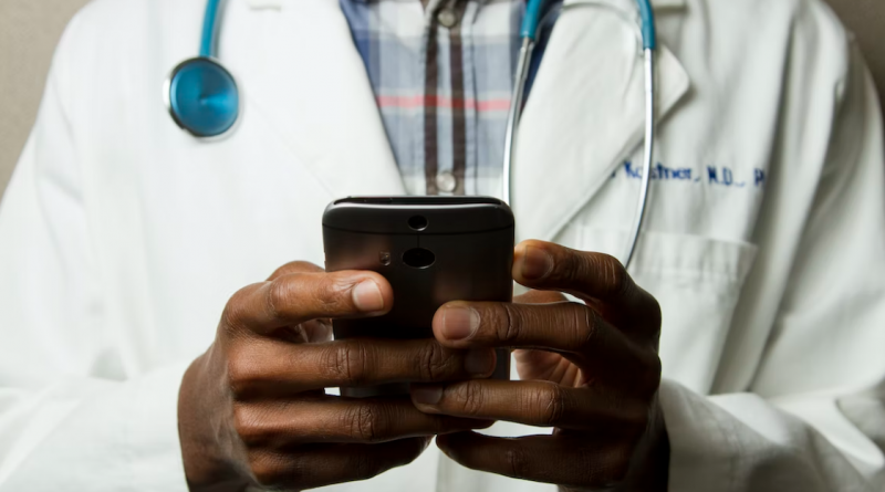 A doctor holding a smart phone with the camera pointed down, as if toward a patient.