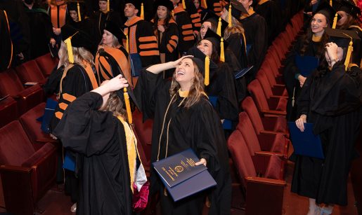 School of Health Professions Graduates look up while smiling with joy during their graduation event.
