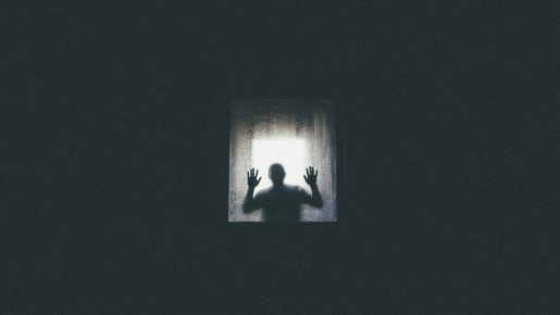 A dark, silhouetted figure standing with arms raised in a lit window.