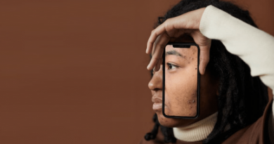 A person looking away from the camera while holding a phone up to their face. The phone has an image of the portion of their face that is being covered.