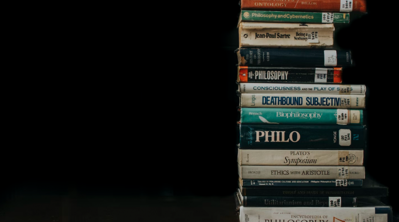 A tall stack of old philosophy books in a dark room.
