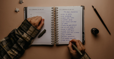 A person in a cozy sweater writing resolutions into a notebook.