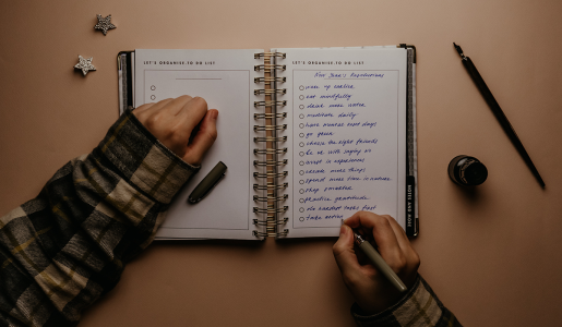 A person in a cozy sweater writing resolutions into a notebook.