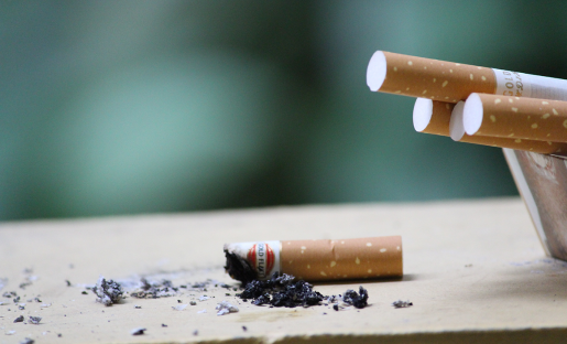 A burnt cigarette on a table next to four un-lit cigarettes.