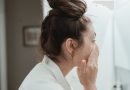 A woman looking into a mirror while cleansing her face