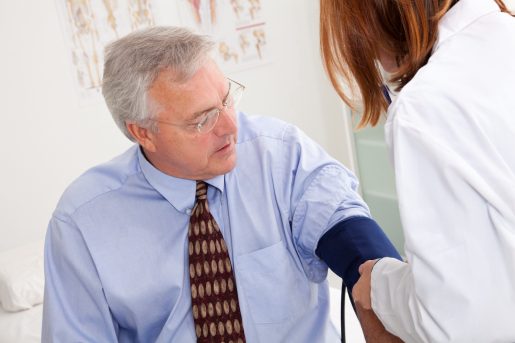 White older man is getting his blood pressure taking at the doctor's office.