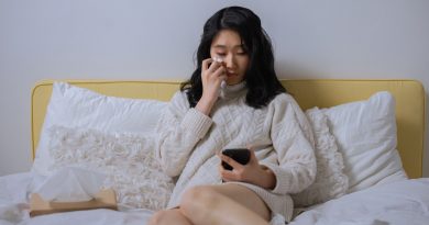 Woman sitting in bed crying while looking at her phone.