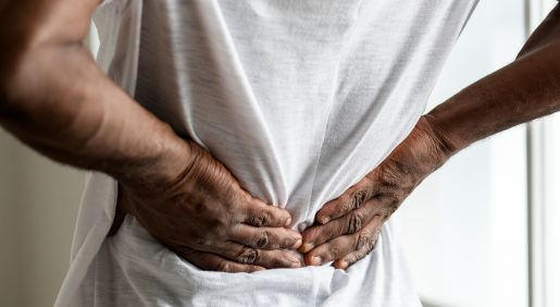 A man holding his back with both hands, as if in pain.