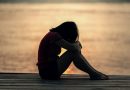 A person sitting on a dock at sunset with their knees pulled up to their head.