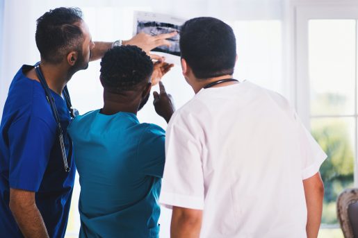 Three doctors examining medical imagery