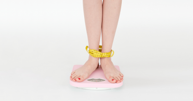 A person standing on a scale with a measuring tape wrapped around their ankles.