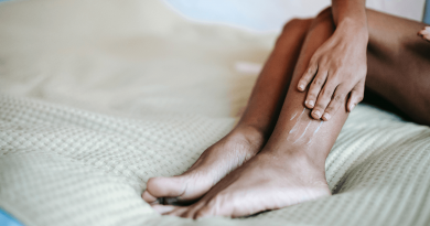 A person laying on a bed, rubbing their calf.