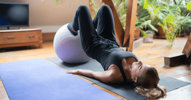 A person in a yoga pose on their back with feet propped up on an exercise ball.