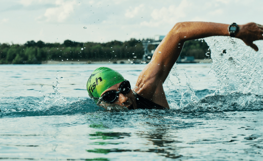 A person wearing goggles swimming in a lake.