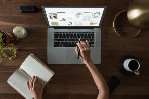 A person working with a laptop and a small journal.