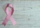 A pink breast cancer ribbon laying on a wooden table